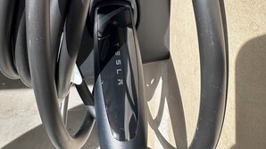 Una estació de càrrega de Tesla amb un cable de càrrega negre connectat.
