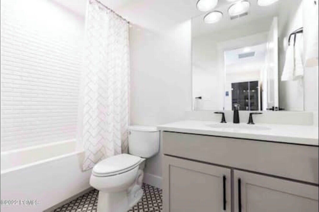 A modern bathroom with a white toilet, a large mirror, and a white sink.