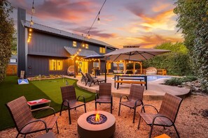 Une terrasse extérieure moderne, dotée d’un foyer, de coins salon et d’un espace piscine.