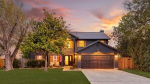 A two-story house with a garage, a well-maintained lawn, and a tree in the foreground. - Timeless-Texas-Inn • Heated Pool Oasis • LUX Vibe (Round Rock)