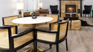 A dining area with a round table and chairs, a fireplace, and a chandelier. - Timeless-Texas-Inn • Heated Pool Oasis • LUX Vibe (Round Rock)