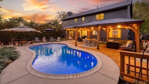 A backyard with a swimming pool, wooden deck, outdoor seating, and a covered patio area. - Timeless-Texas-Inn • Heated Pool Oasis • LUX Vibe (Round Rock)