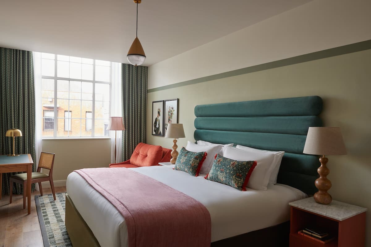 A neatly arranged hotel room with a large bed, a desk, and a chair.