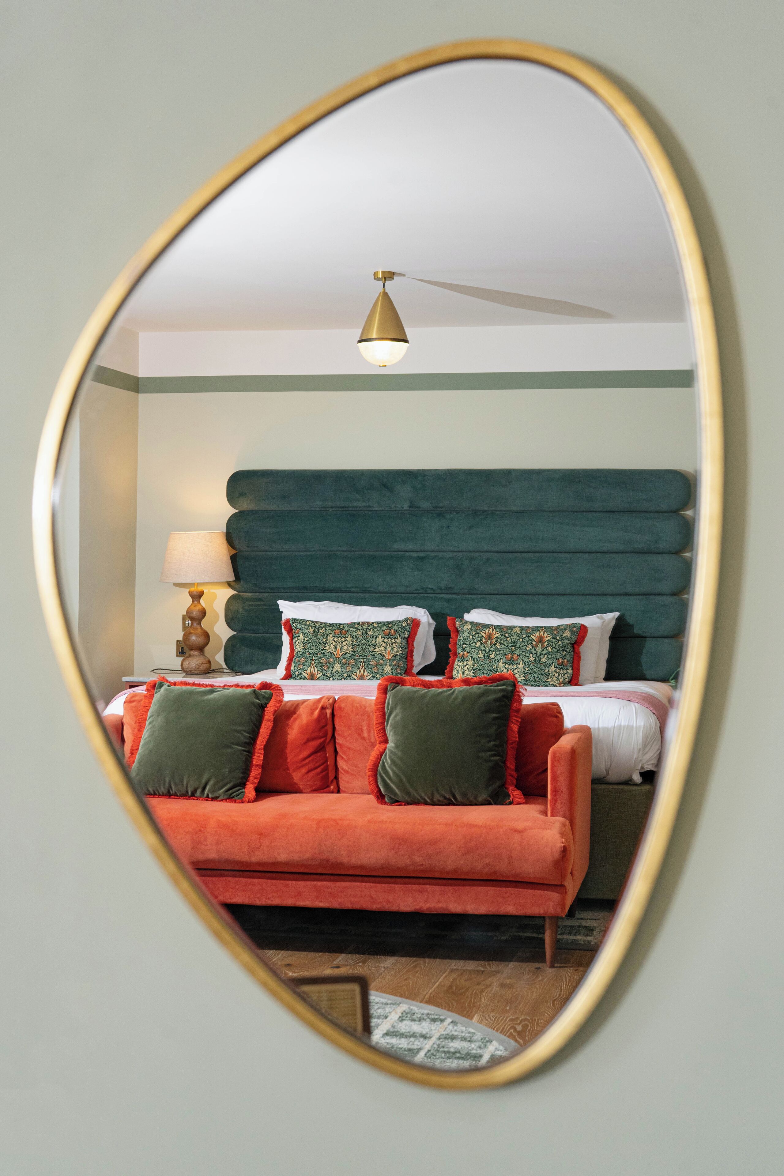 A bedroom with a bed, a red sofa, and a lamp.