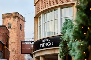 Un hotel llamado 'Hotel Indigo' con una fachada clásica de ladrillo y grandes ventanales.
