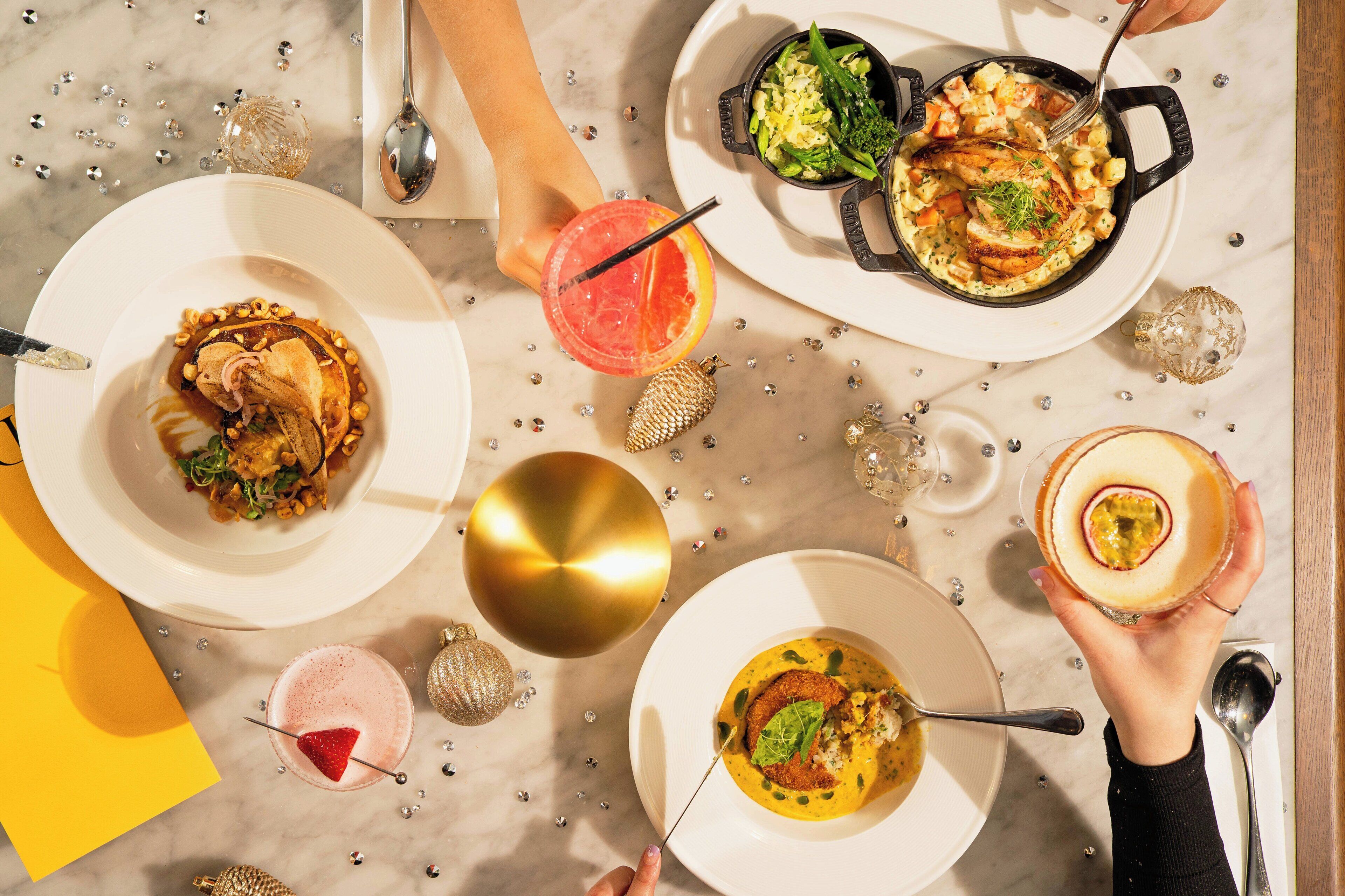 A table with various dishes and drinks, surrounded by decorative elements like a golden ornament and small ornaments.