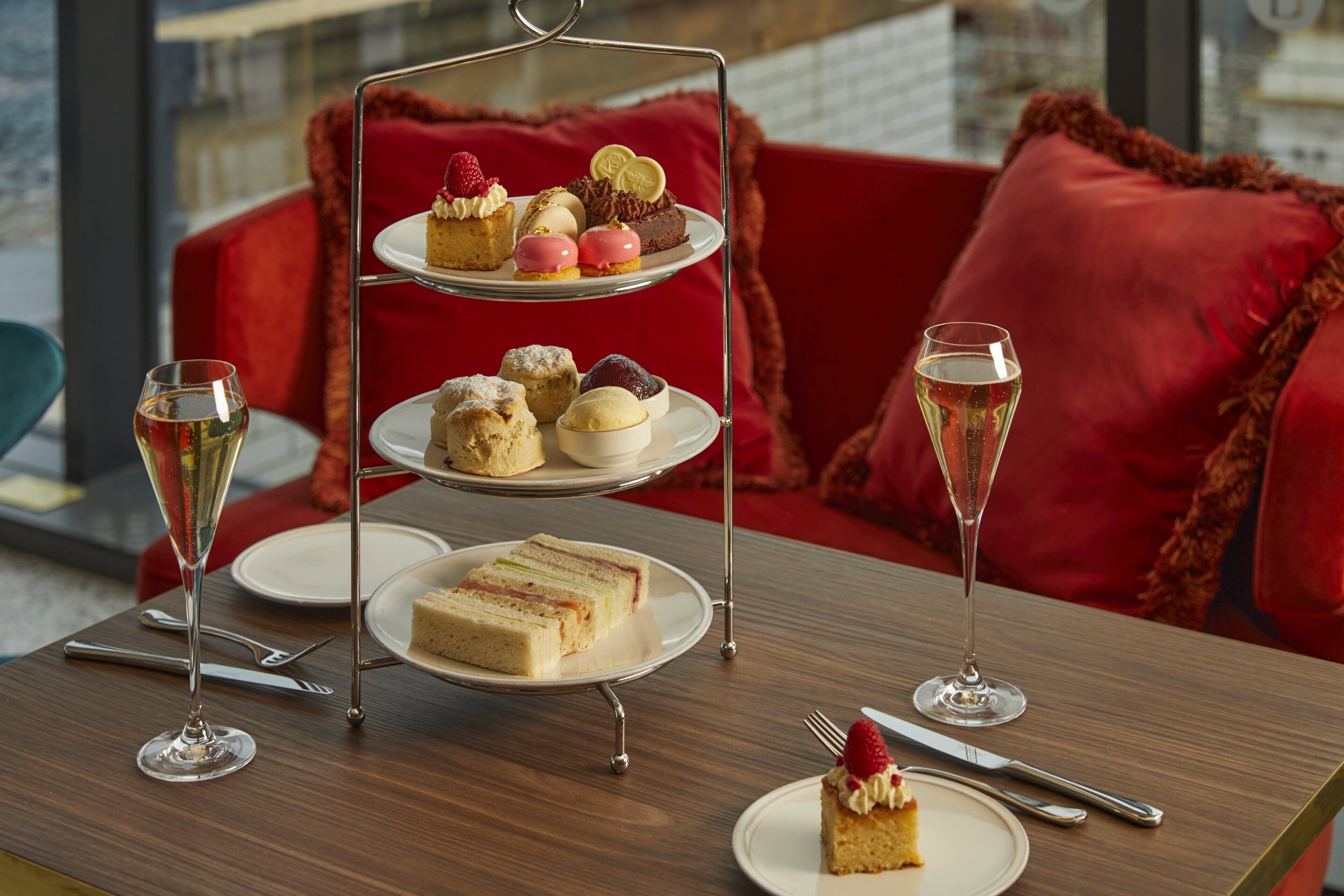 Ein dreistöckiger Dessertteller mit verschiedenen Backwaren und einem Glas Champagner auf einem Holztisch.