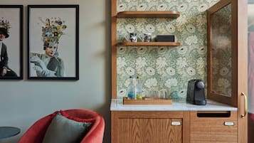 A room with a wooden cabinet, a red chair, and two framed artworks on the wall.