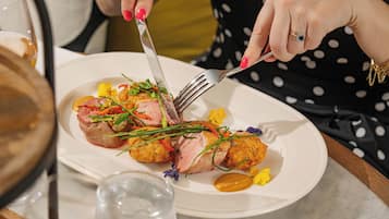 Una persona cortando comida en un plato con un tenedor y un cuchillo.