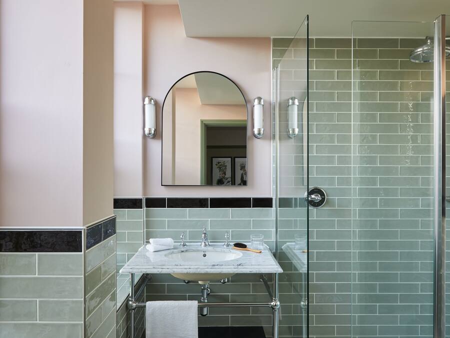 A bathroom with a glass-enclosed shower, a sink with a mirror above it, and a towel rack.