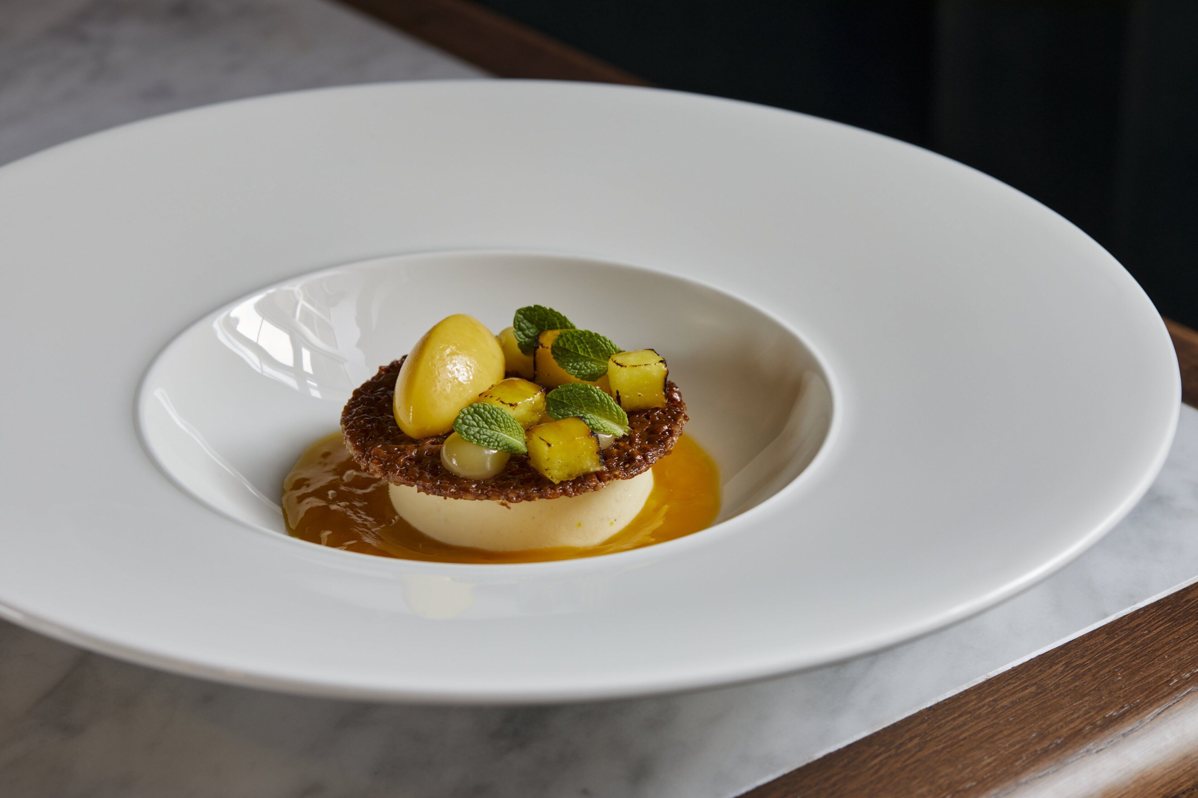 A dessert on a white plate with a caramelized crust and mint leaves.