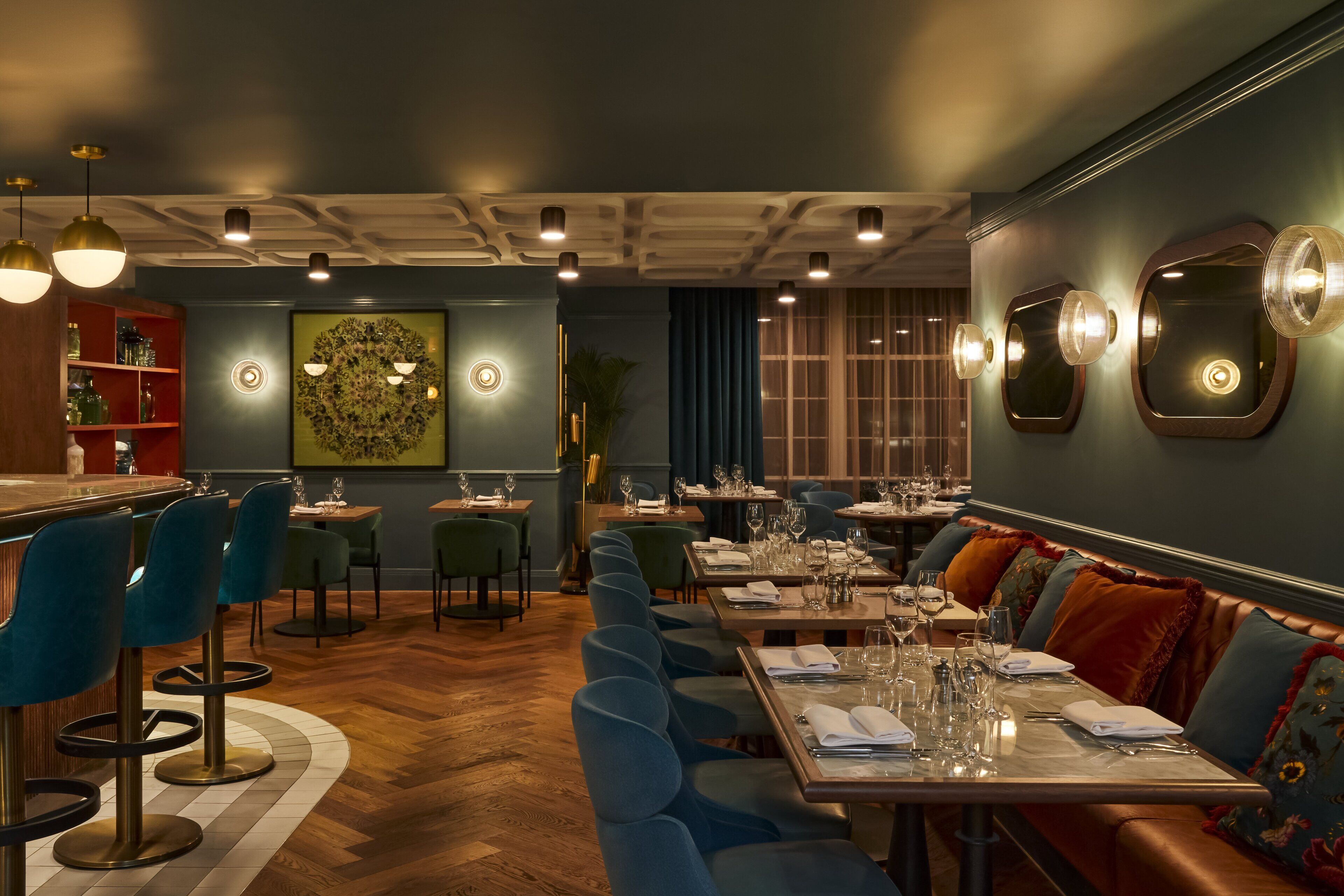 Ein Restaurant mit Barbereich, blau gepolsterten Sitzmöglichkeiten und Holzboden.