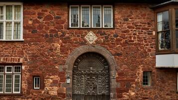 A stone building with a large arched entrance, multiple windows, and a decorative emblem above the door.
