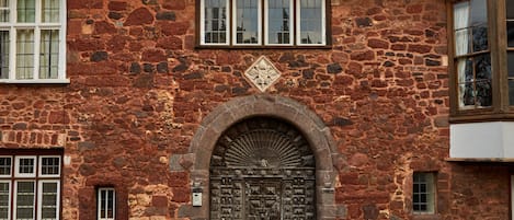 A stone building with a large arched entrance, multiple windows, and a decorative emblem above the door.