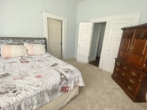 Une chambre à coucher avec un lit, deux portes et une commode en bois.