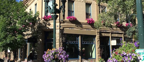 Un edificio histórico con una imponente torre de reloj, grandes ventanales y jardineras en la fachada.