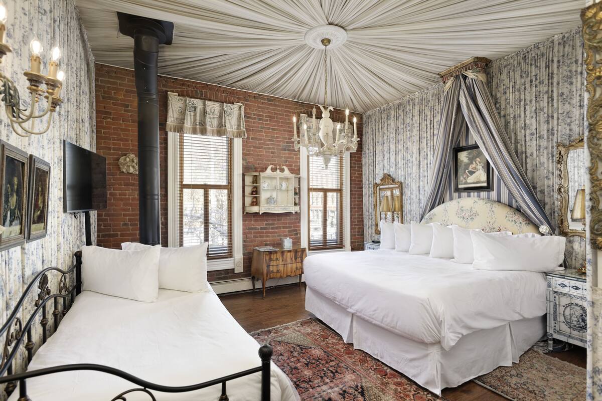 Ein Schlafzimmer mit zwei Betten, einer Ziegelwand und einer Kristallleuchtre.
