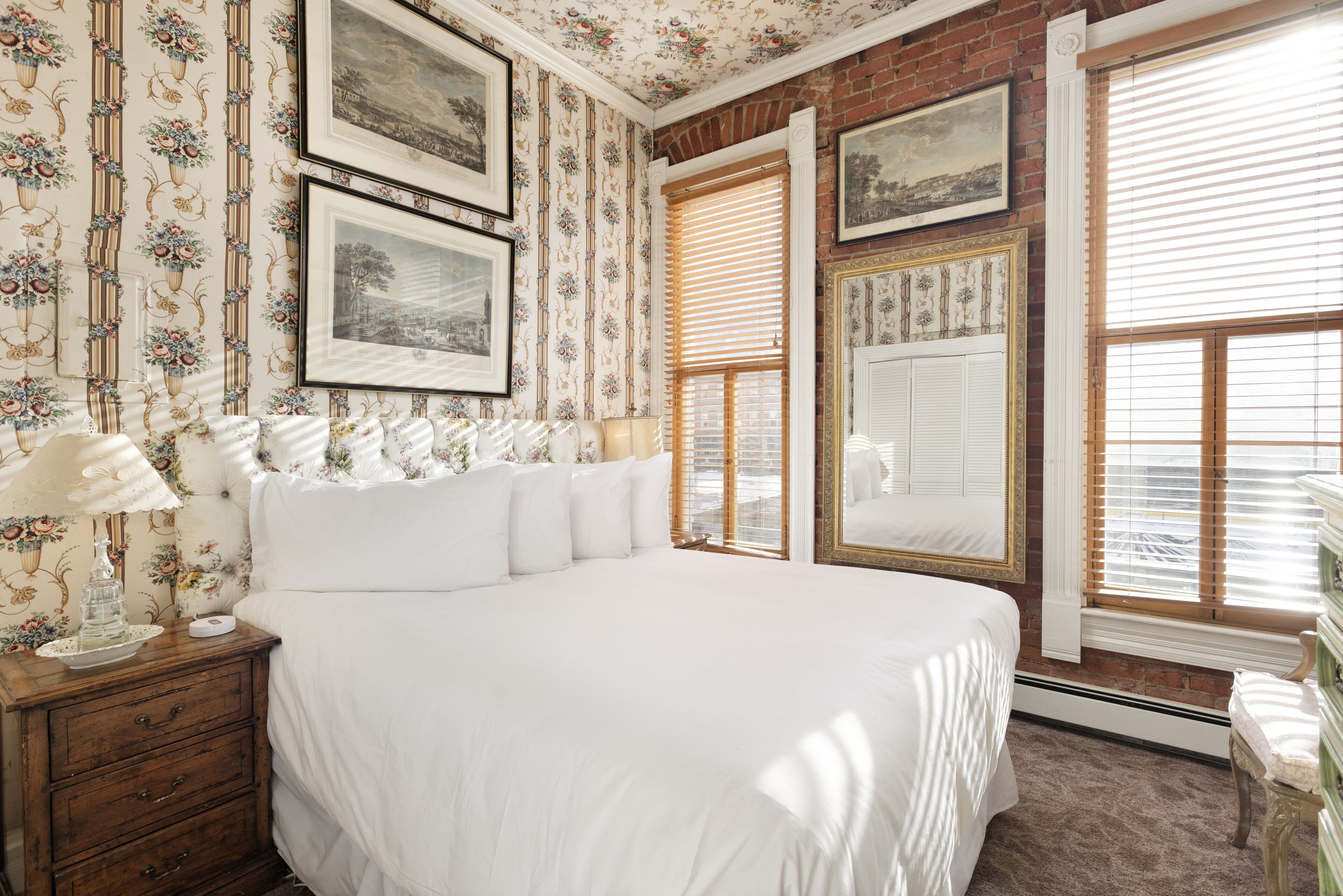 A bedroom with a large bed, wooden nightstand, and a dresser.