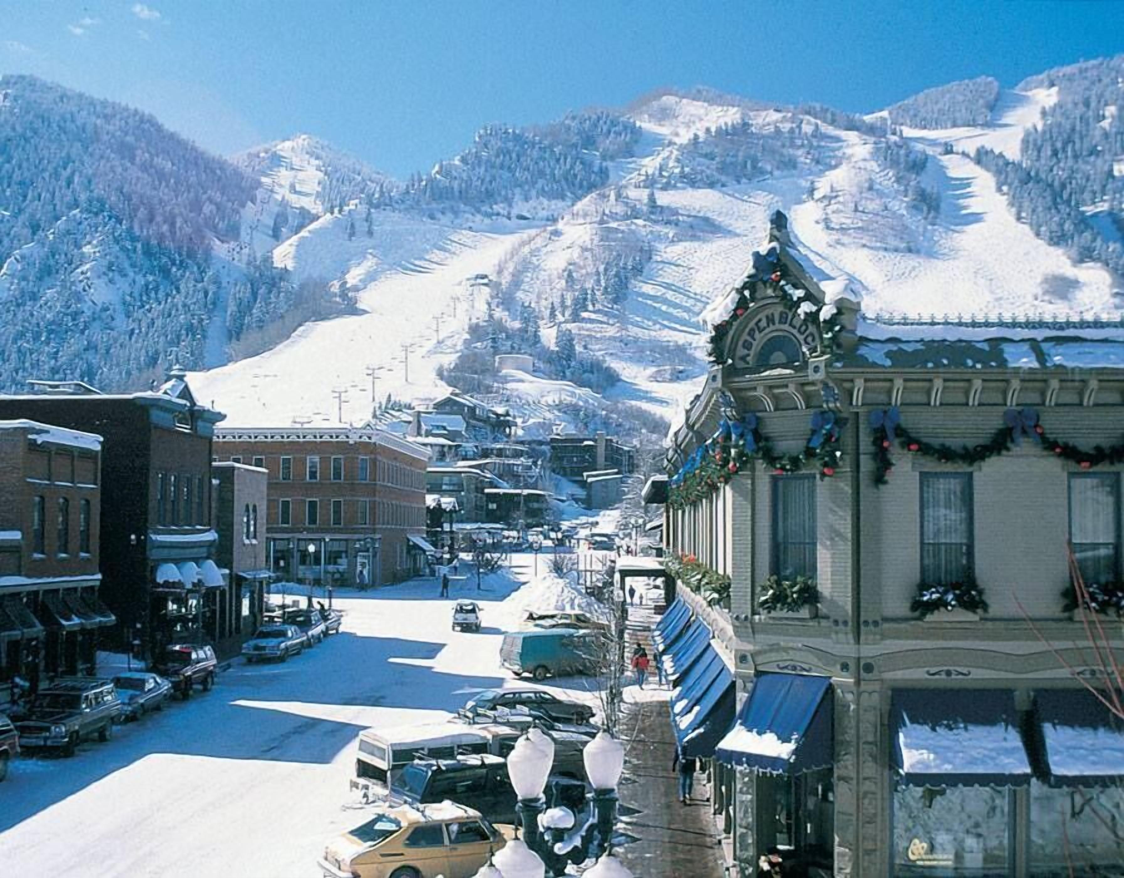 Uma cidade coberta de neve, com edifícios e uma montanha ao fundo.