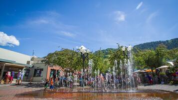 Una plaza pública con una fuente de agua, pavimento de ladrillo y gente.