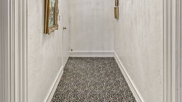 A hallway with a chandelier, framed pictures, and a leopard print floor.