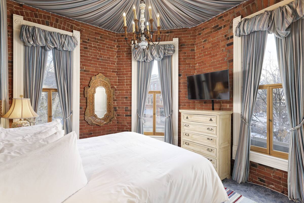 Ein Schlafzimmer mit einem großen Bett, einem Schminktisch, einem Fernseher und einem Kronleuchter.