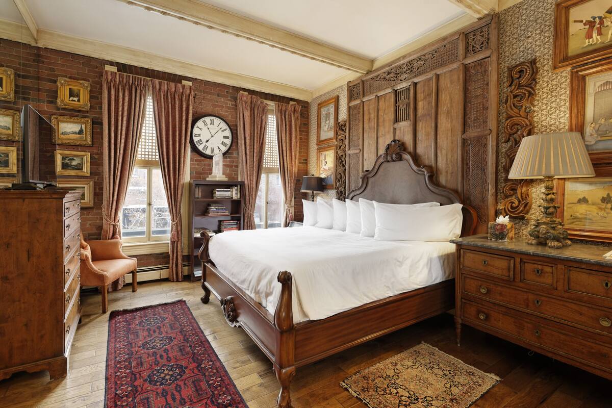 Ein traditionell eingerichtetes Schlafzimmer mit einem großen Bett, einem Holzschrank und einer Wanduhr.