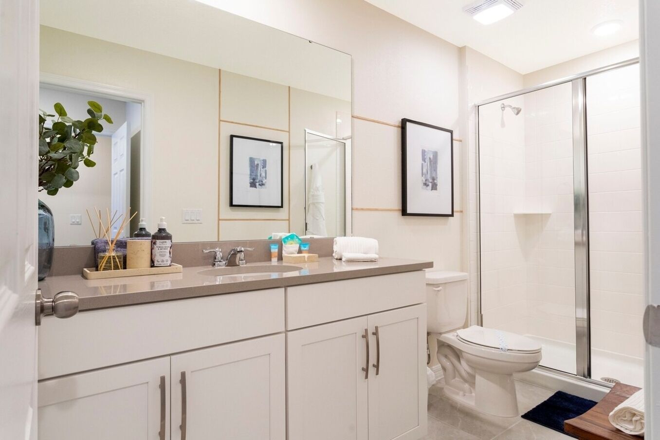 A modern bathroom with a large mirror, a shower, and a toilet.