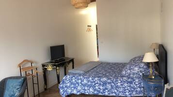 Quarto com cama, televisão, mesa de cabeceira, cadeira e luminária pendente.