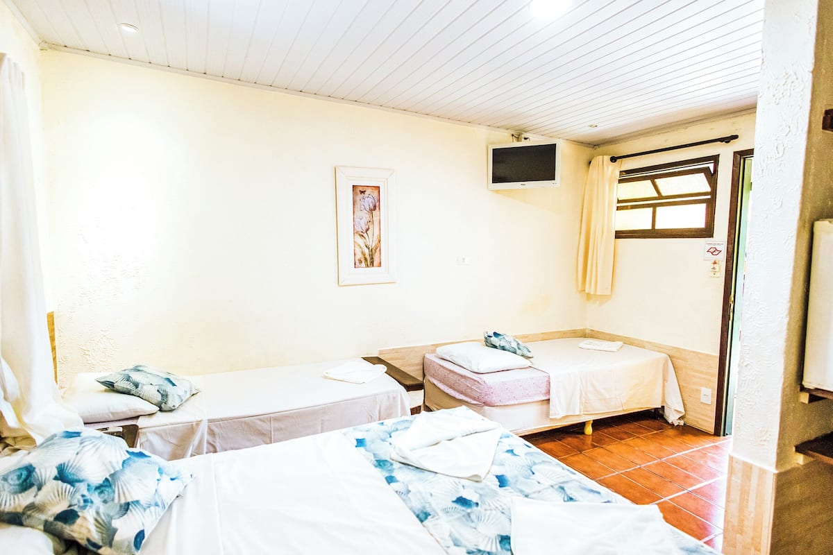 Una habitación con dos camas, televisión y ventana con cortinas.