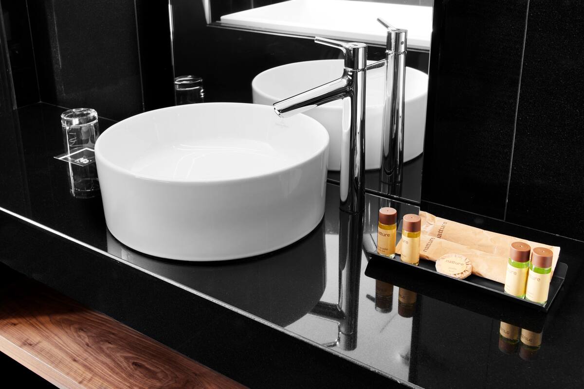 A modern bathroom with a white sink, chrome faucet, and a mirror.