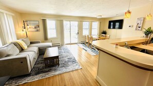 A modern living room with a sofa, a coffee table, and a dining area with chairs.