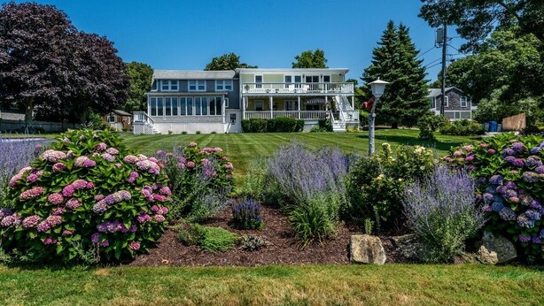 A two-story house with a front porch and a well-maintained lawn.