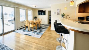 A modern kitchen with a bar area, wooden dining table, and chairs.