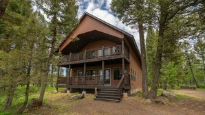 Une cabane à deux étages dotée d’un balcon, entourée d’arbres.
