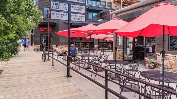 A boardwalk plaza with outdoor seating and a variety of establishments including a pizzeria and wellness center. - Downtown condo short walk to lake, patio and awesome common area (Grand Lake)