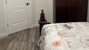 Ein Schlafzimmer mit einem Holzschrank, einer weißen Tür und einem Bett mit blumigem Überwurf.