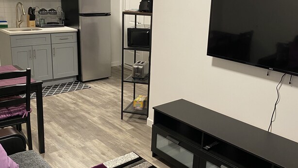Ein modernes Wohnzimmer mit einem grauen Sofa, einer schwarzen Unterhaltungsecke und einem flachbildfernseher an der Wand.