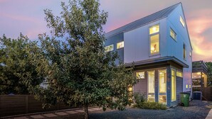 Une maison moderne à deux étages, dotée d’un toit en pente, de grandes fenêtres et d’un jardin bien entretenu.