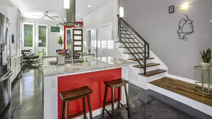 Une cuisine moderne dotée d’un îlot central, d’appareils électroménagers en acier inoxydable et d’un mur d’accent rouge.
