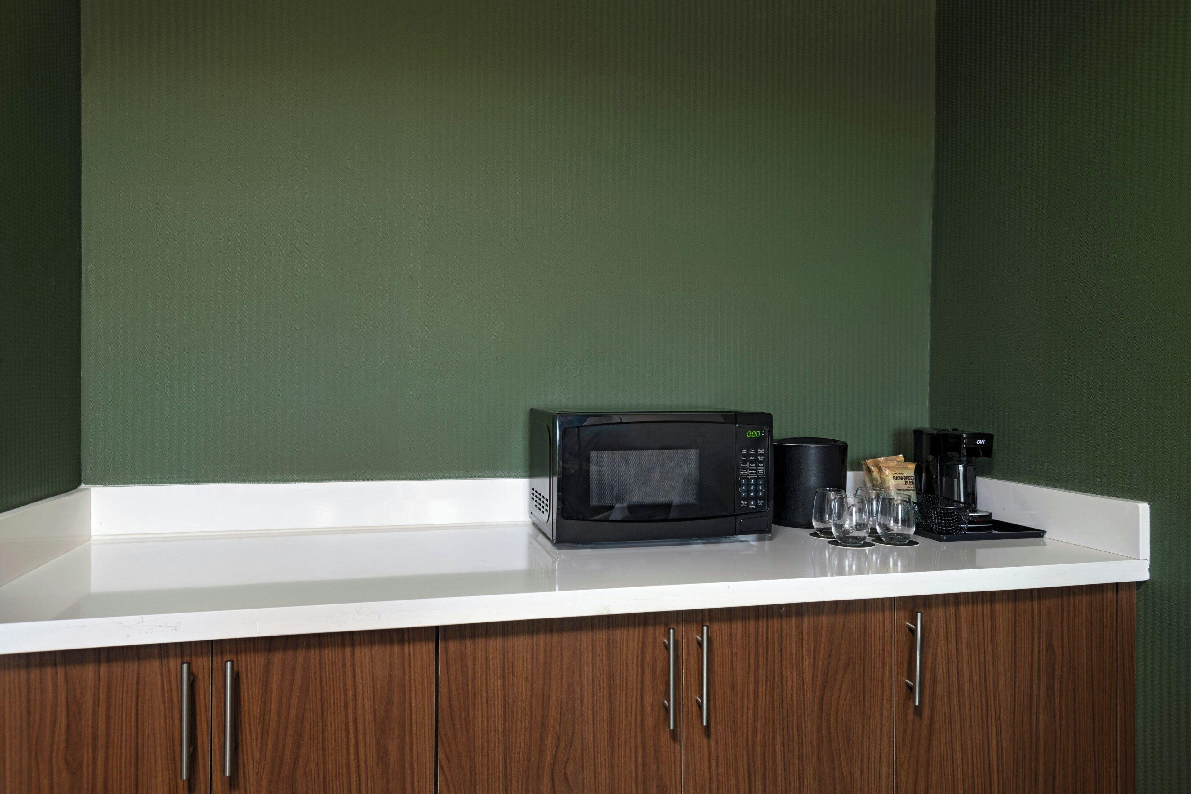 A kitchen counter with a microwave, coffee maker, and a bag of coffee.