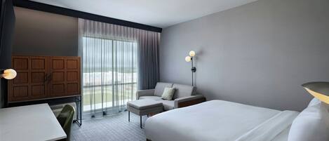 A hotel room with a bed, a desk, a chair, a sofa, and a wardrobe.