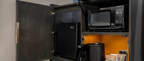 A compact kitchenette with a microwave, coffee maker, and storage for coffee beans.