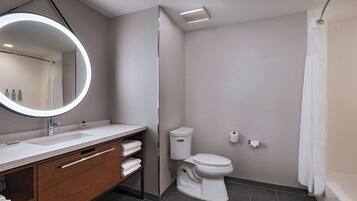 A modern bathroom with a round mirror, white sink, and toilet.