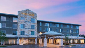 Een Courtyard by Marriott hotel met een gevel van natuursteen, meerdere verdiepingen en een overdekte ingang.