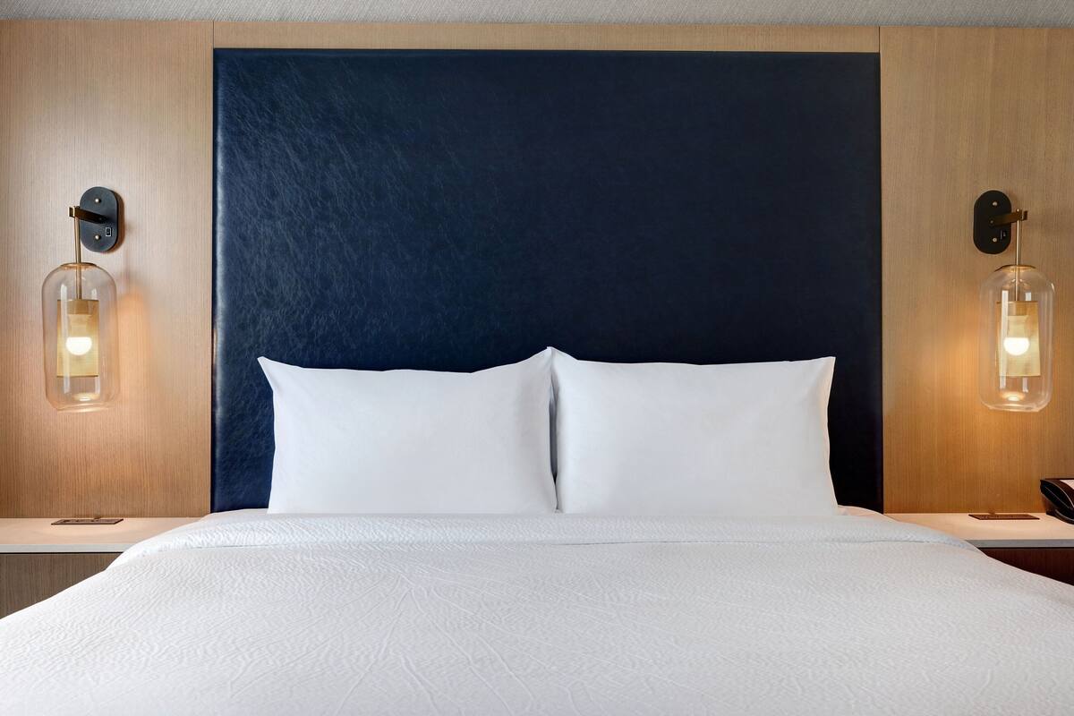 Ein Hotelzimmer mit einem großen Bett, zwei Nachttischen und Wandlampen.