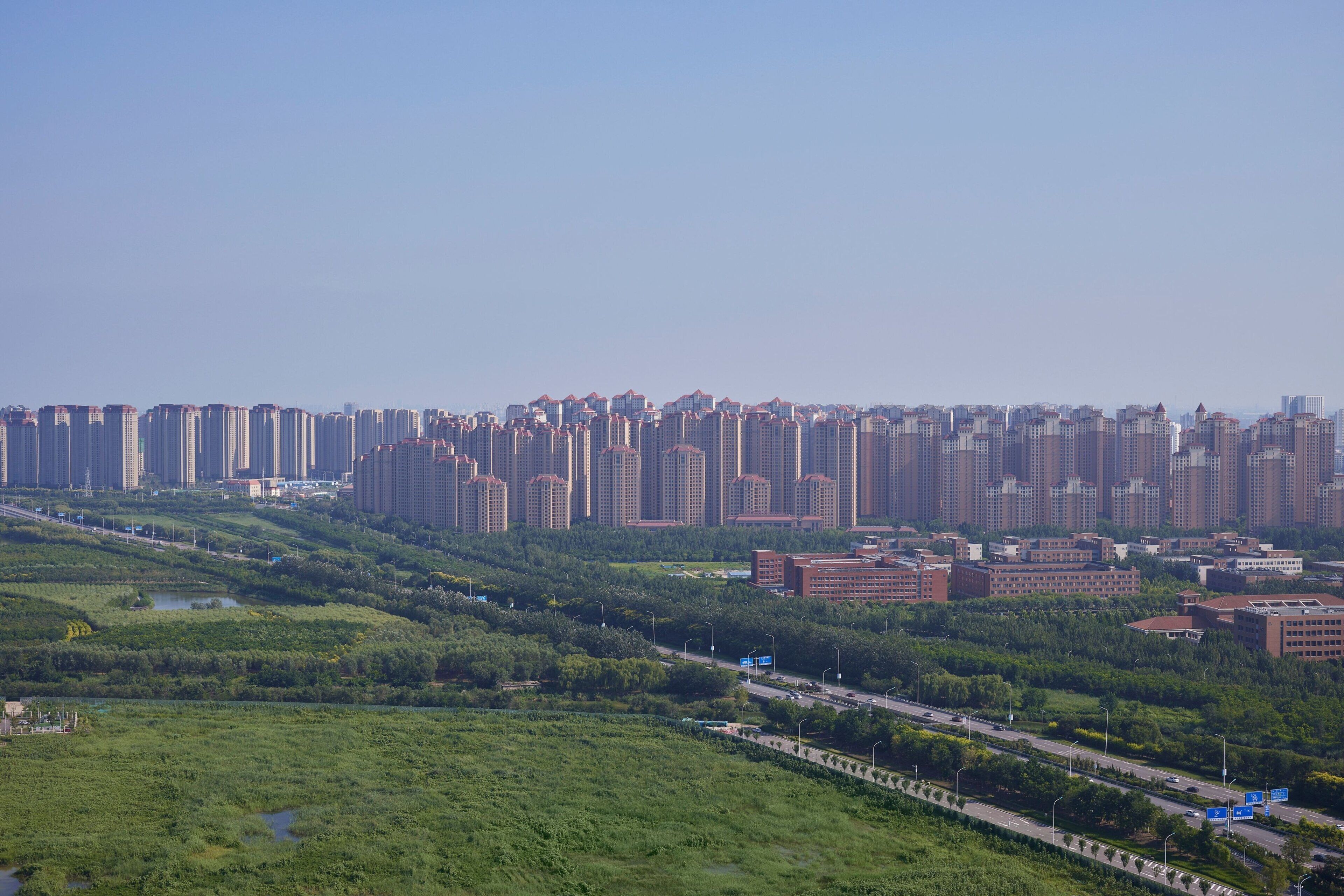 A high-rise residential area with dense apartment buildings, a highway, and green spaces.
