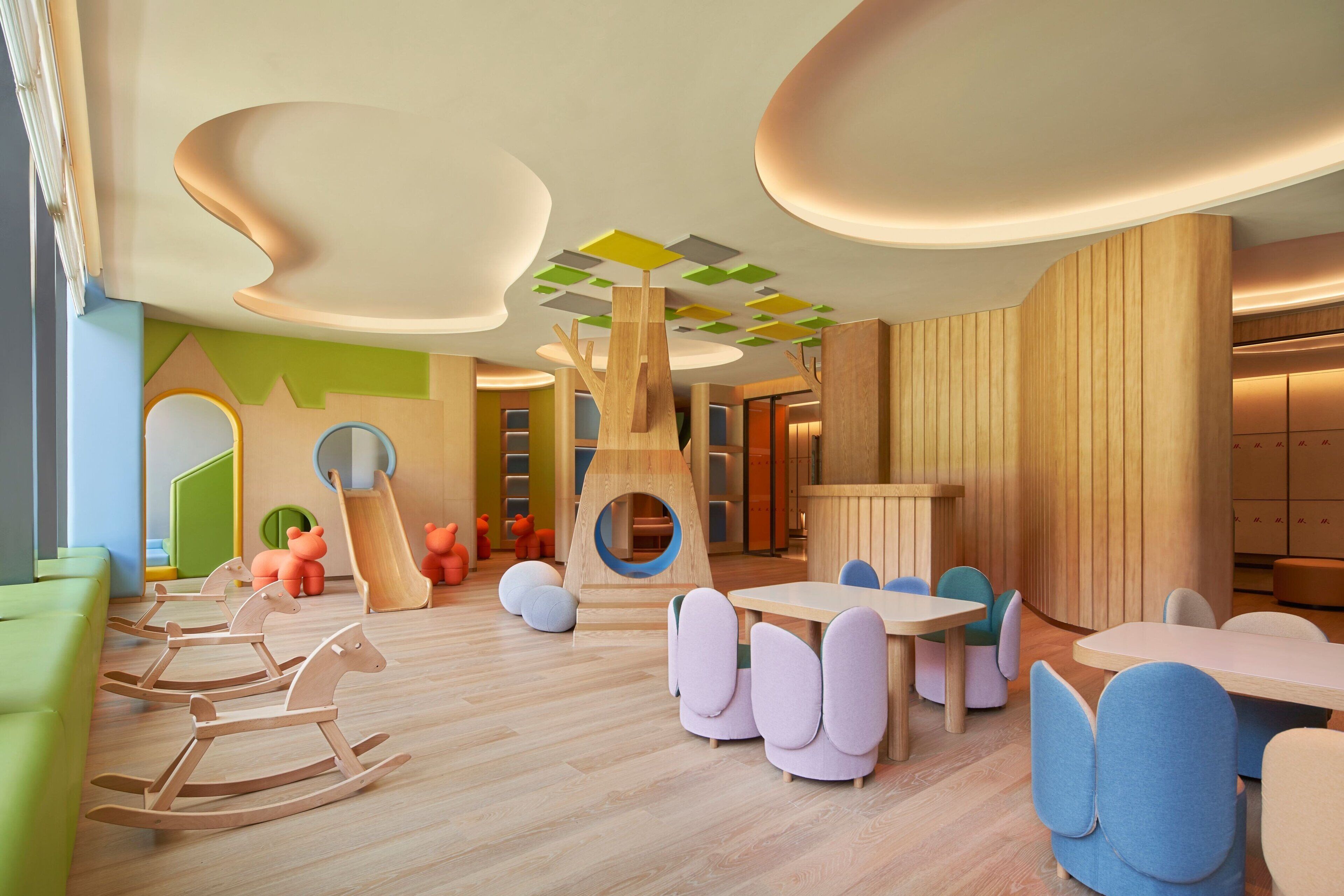 A modern children's play area with wooden furniture, a slide, and a circular play structure.