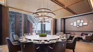 A modern dining area with a round table set for six, surrounded by dark chairs. - Tianjin Marriott Hotel National Convention And Exhibition Center (Tianjin)