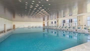 Una piscina techada, sillones reclinables de piscina